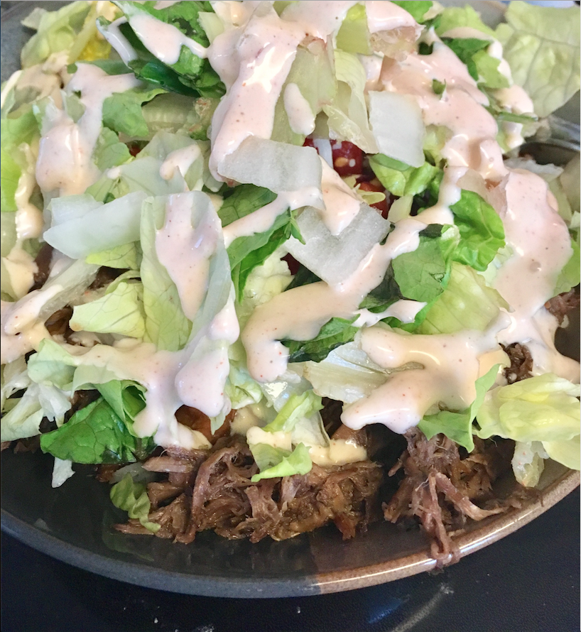 Closeup of rice bowl with lettuce, meat and dressing