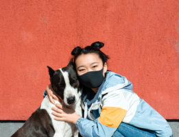 girl with mask and black and white dog