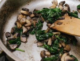 Spinach and mushrooms being sauteed in a pan