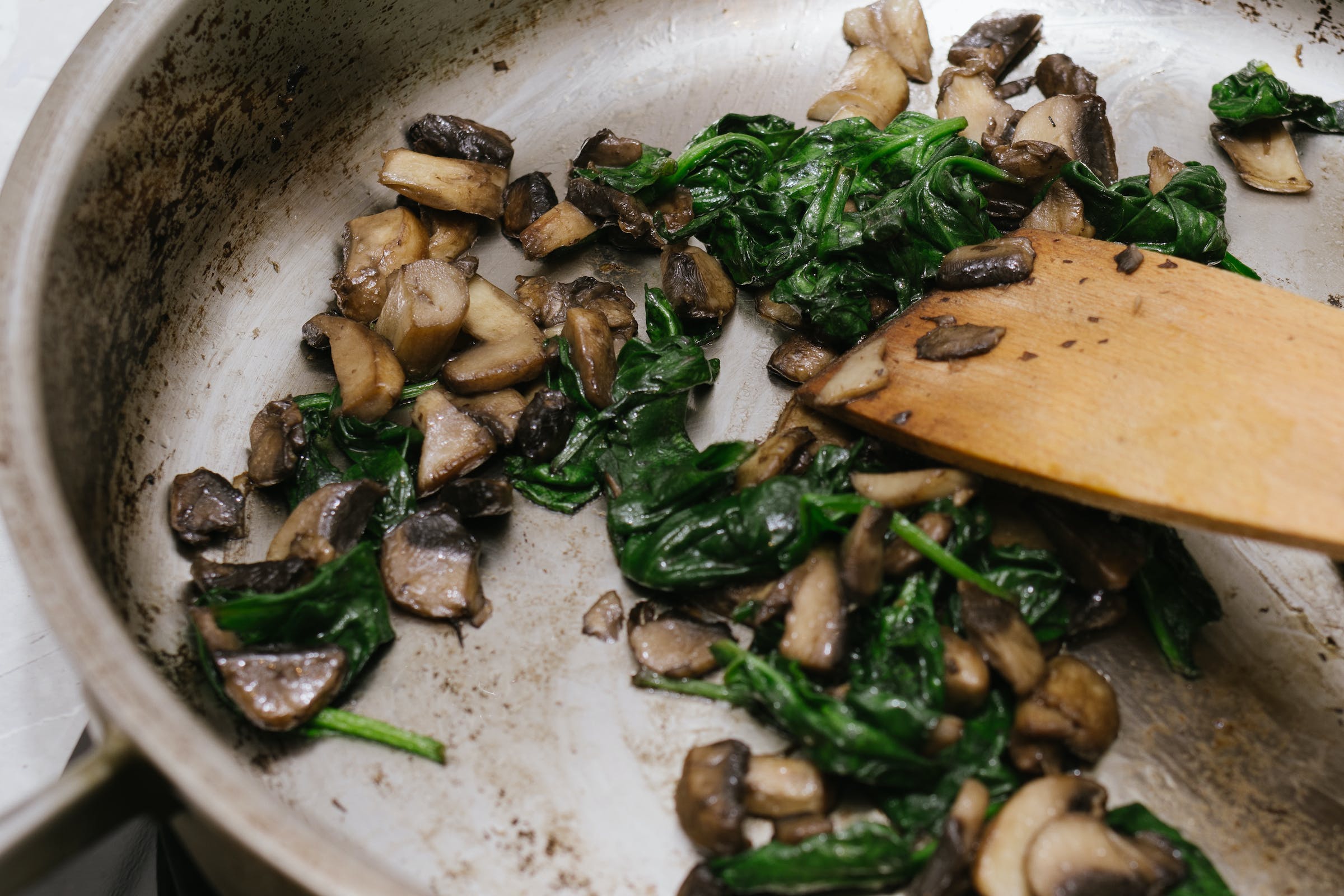 Spinach and mushrooms being sauteed in a pan