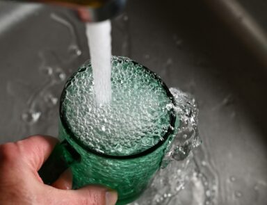 Tap water pouring into cup from sink