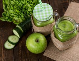 Green juice in cup next to apple