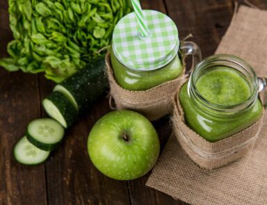 Green juice in cup next to apple