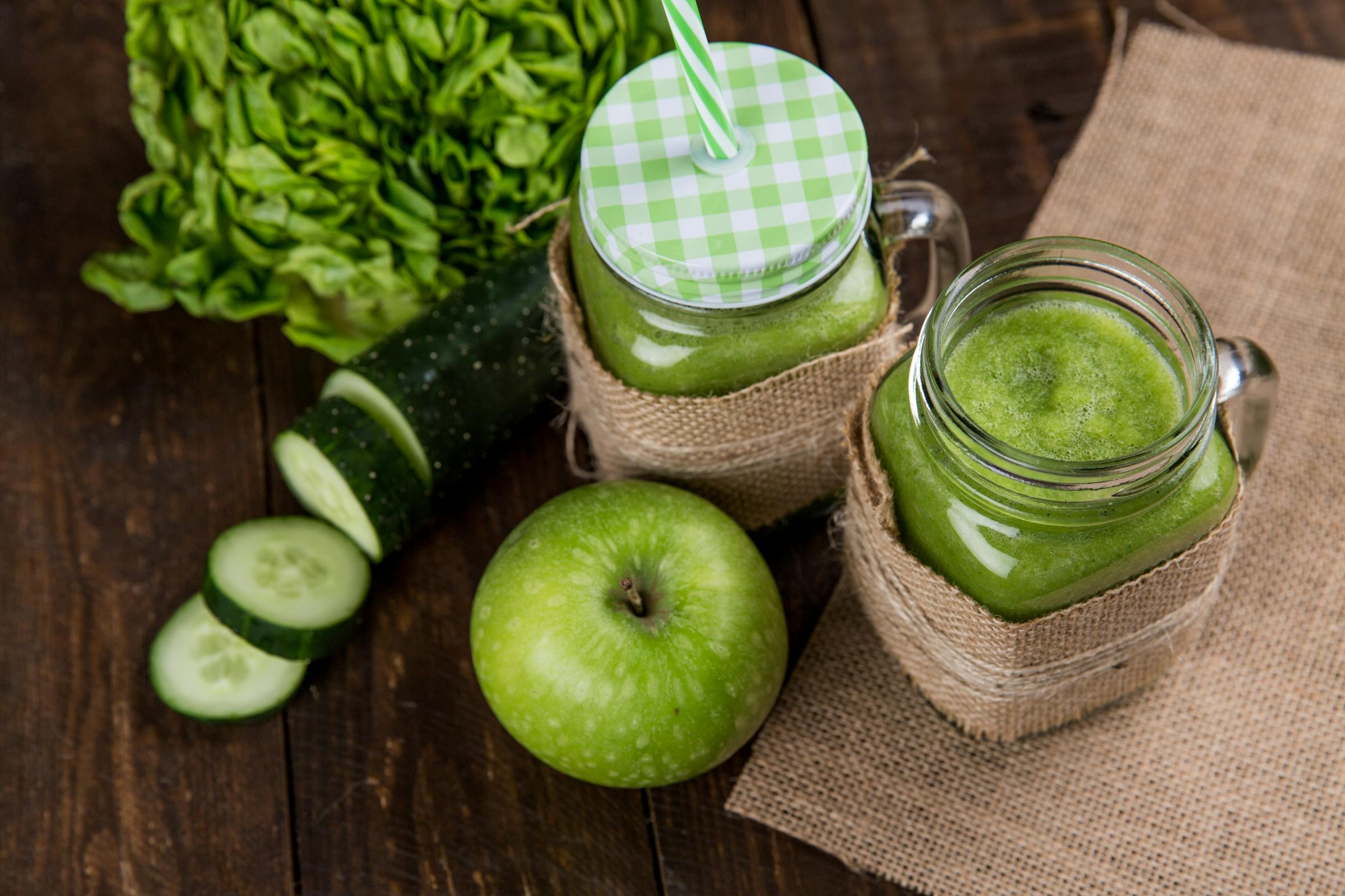 Green juice in cup next to apple