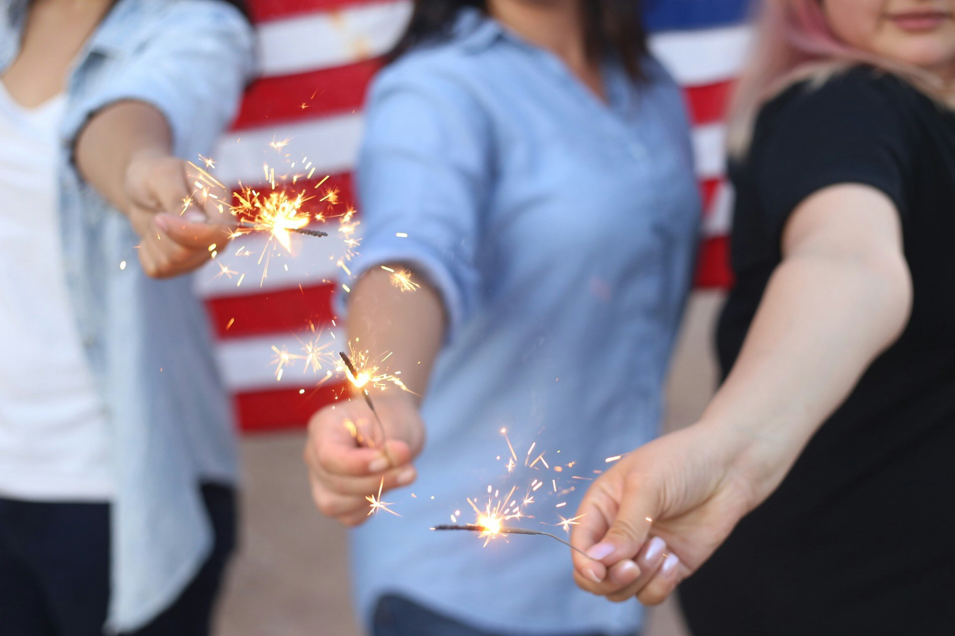 Closeup of three people holding sparklers for the fourth of july