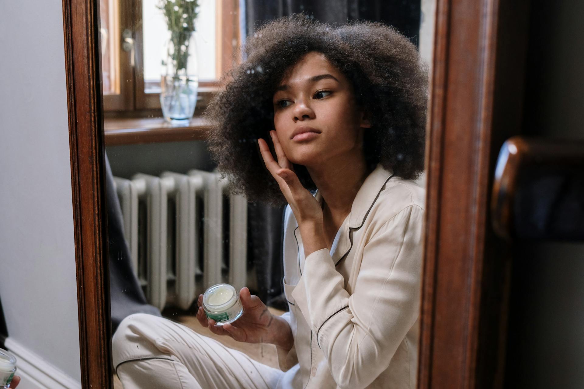 Woman looking in mirror using skin ca